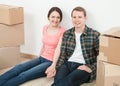 Happy young man and woman sitting near cardboard boxes Royalty Free Stock Photo