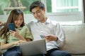 Happy young man and woman using laptop together, couple shopping or chatting online, using internet banking services Royalty Free Stock Photo