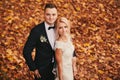 Happy young married couple in golden yellow fall autumn park. beautiful bride and stylish groom hugging in wedding day Royalty Free Stock Photo