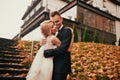 Happy young married couple in golden yellow fall autumn park. beautiful bride and stylish groom hugging in wedding day Royalty Free Stock Photo