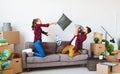 Happy young married couple moves to new apartment and laughing, jump, fight pillows