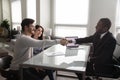 Happy young couple shaking hands with african american financial advisor. Royalty Free Stock Photo