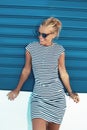 Happy young mediterranean blonde woman posing at blue roller shutter