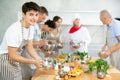 Happy young man attendee of cooking course learning how to mix sauce Royalty Free Stock Photo