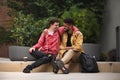 Happy young man with Down syndrome and mentoring friend sittingwith arms around outdoors