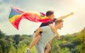 Happy young men, gay family with flying LGBT rainbow flag having fun outdoors. Joyful gay couple together in a park Royalty Free Stock Photo