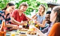 Happy young men and women toasting healthy orange fruit juice at farm house picnic - Life style concept with alternative friends Royalty Free Stock Photo