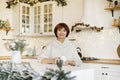 Happy young middle aged woman enjoying drinking tea or coffee in kitchen with Christmas decor Royalty Free Stock Photo