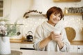 Happy young middle aged woman enjoying drinking tea or coffee in kitchen with Christmas decor Royalty Free Stock Photo