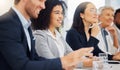 Happy young mixed race businesswoman listening to a presentation during a meeting in an office boardroom alongside her Royalty Free Stock Photo