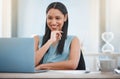 Happy young mixed race businesswoman smiling while enjoying working on a laptop sitting in a chair in an office at work Royalty Free Stock Photo