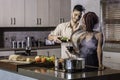 Happy young mixed race couple drinking wine cooking dinner in kitchen Royalty Free Stock Photo