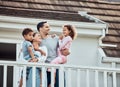 Happy young mixed race family with two children standing outside on their balcony at home. Loving couple with their Royalty Free Stock Photo