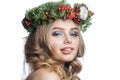 Happy young model woman with wavy blonde hair, makeup and green winter wreath isolated on white background. Beautiful female face Royalty Free Stock Photo