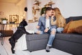 Happy young modern couple sitting on the sofa at home with their cute dog Royalty Free Stock Photo