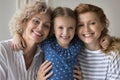 Happy young mom and grandma hugging cheerful child girl