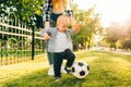 Happy young mom and her little son play soccer together outdoors Royalty Free Stock Photo