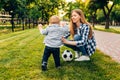 Happy young mom and her little son play soccer together outdoors Royalty Free Stock Photo