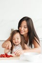 Happy young mom with little cute asian daughter cut strawberry Royalty Free Stock Photo