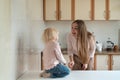 Happy young mom and little daughter fooling in the kitchen