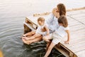 Happy young mom with little girls sitting on wooden bridge near lake, pond on summer. Mother and two child daughter Royalty Free Stock Photo