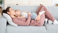 Happy Young Mom Lying With Her Adorable Toddler Boy On Couch Together