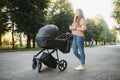 Happy young mother with baby in buggy walking in autumn park Royalty Free Stock Photo