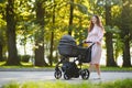 Happy young mother with baby in buggy walking in autumn park Royalty Free Stock Photo