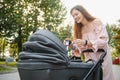 Happy young mother with baby in buggy walking in autumn park Royalty Free Stock Photo