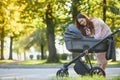 Happy young mother with baby in buggy walking in autumn park Royalty Free Stock Photo