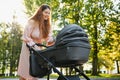 Happy young mother with baby in buggy walking in autumn park Royalty Free Stock Photo