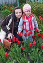 Happy young Mother with baby playing in a field of tulips