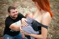 Happy young mother breastfeed newborn baby, father sits next to