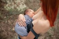 Happy young mother breastfeed newborn baby on walk.