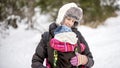 Happy young mother carrying her baby in a carrier