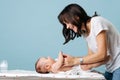 Young beautiful mom changes baby`s diaper and smiles at him Royalty Free Stock Photo