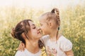 Happy young mother cuddles with her daughter in the summer on the field of rape. Happiness with family