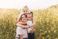 Happy young mother cuddles with her daughters in the summer on the field of rape. Happiness with family