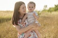 Happy young mother with cute baby son joyful exploring the world on field at sunny day Royalty Free Stock Photo