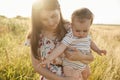 Happy young mother with cute baby son joyful exploring the world on field at sunny day Royalty Free Stock Photo