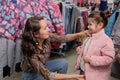 Girl trying on a jacket for the winter in a children`s clothing store. Happy young mother and daughter shopping