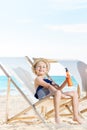 Girl sitting on beach chairs and holding sun scre