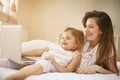 Happy young mother with daughter using laptop on bed at home. Royalty Free Stock Photo