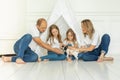 Happy young mother and father with two little daughters sitting on floor, looking at little puppy dog pet Royalty Free Stock Photo