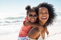 Happy young mother giving laughing daughter piggyback ride at beach Royalty Free Stock Photo