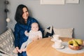 Happy young mother having breakfast in modern kitchen with her baby daughter Royalty Free Stock Photo