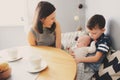 Happy young mother having breakfast in modern kitchen with her baby daughter and kid son Royalty Free Stock Photo