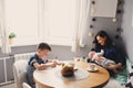 Happy young mother having breakfast in modern kitchen with her baby daughter and kid son Royalty Free Stock Photo