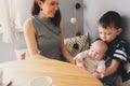 Happy young mother having breakfast in modern kitchen with her baby daughter and kid son Royalty Free Stock Photo