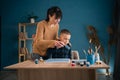 happy young mother helps son to paint acrylic painting on canvas at home. concept of joint pastime. Royalty Free Stock Photo